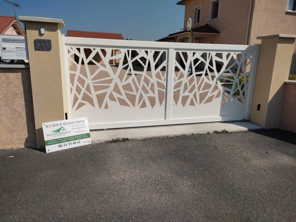 Portail blanc ajouré à motifs géométriques et soubassement plein, installé entre deux piliers beiges.